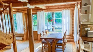 Una cabaña de madera con comedor, escaleras y vistas al exterior.