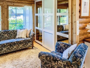 A cozy room with two patterned sofas, a large sliding glass door, and a wooden interior. - Hartolan ilo by Interhome (Hartola)