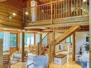 A spacious wooden interior with a high ceiling, a staircase leading to an upper level, and a kitchen area. - Hartolan ilo by Interhome (Hartola)