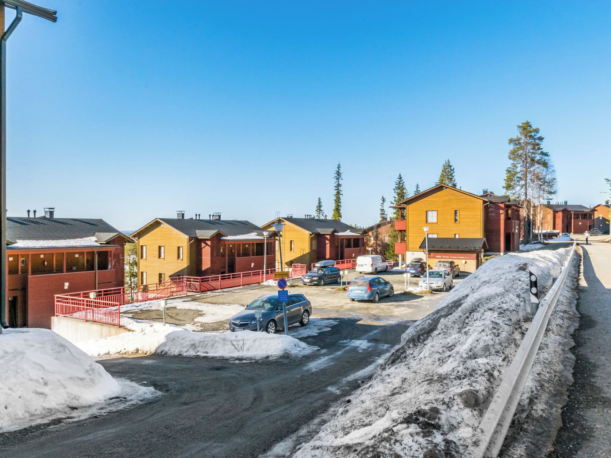 Bairro residencial com casas, estacionamento e uma rua coberta de neve.