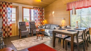 A cozy interior with a wooden ceiling, a dining area with a table and chairs, a sofa, and a patterned curtain. - Länsirinne e 20 by Interhome (Kuusamo)