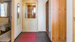 A hallway with a wooden door, a red mat, and a mirror on the wall. - Länsirinne e 20 by Interhome (Kuusamo)