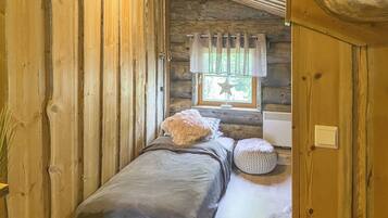A cozy bedroom with a single bed, a window with curtains, and a small bedside table.