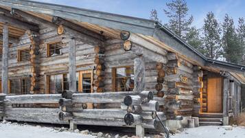 A log cabin with a wooden porch, large windows, and a door.