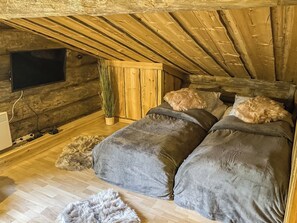 A cozy attic bedroom with two beds, a TV, and a plant. - Mäentähti b by Interhome (Kuusamo)