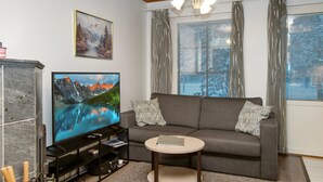 A living room with a television, sofa, and coffee table. - Alppitalo punatähti 7 as 2 by Interhome (Nilsiä)