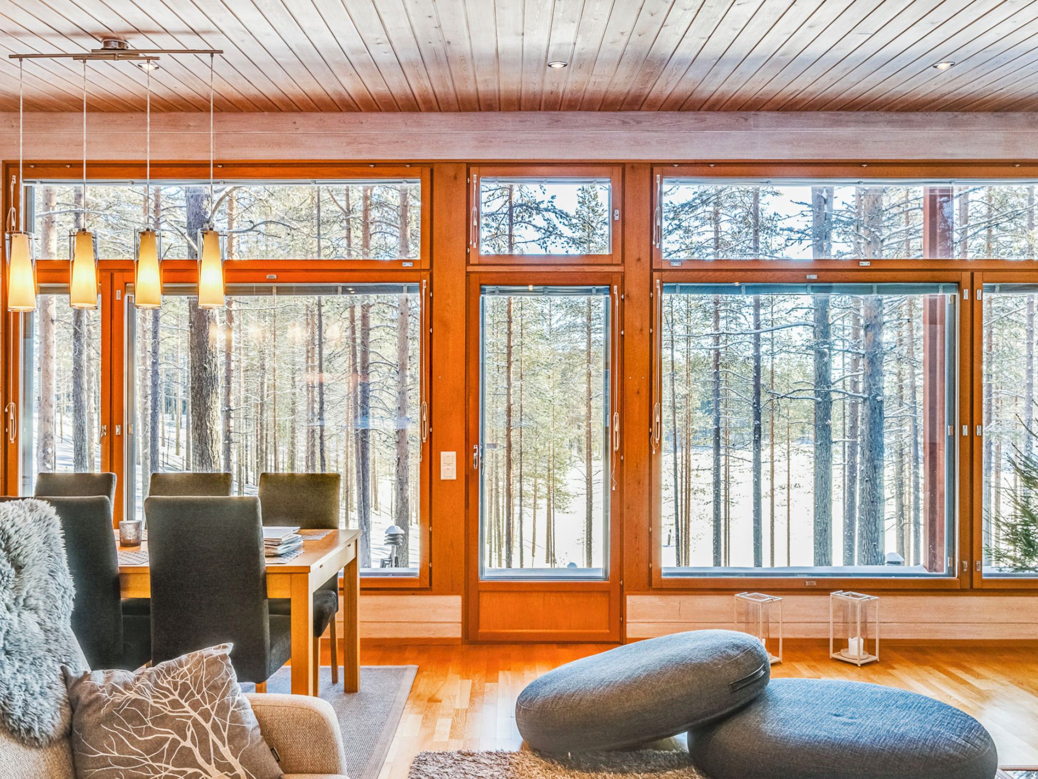 Un interior moderno con ventanas amplias, pisos de madera y un comedor.
