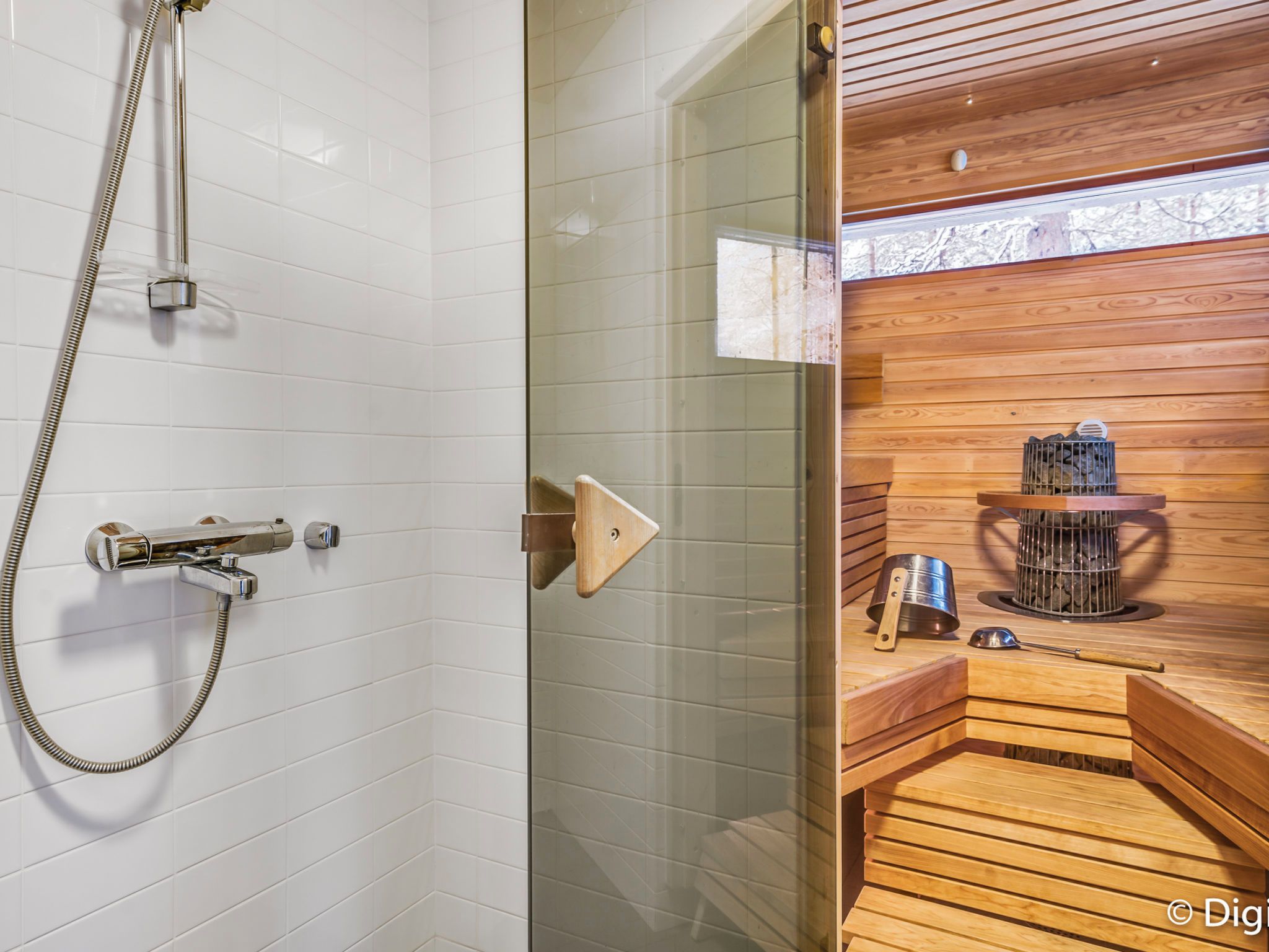 A modern bathroom with a glass shower enclosure, a wooden sauna area, and a visible sauna heater.