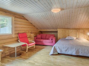 Une pièce confortable avec un lit, un fauteuil rouge, un canapé rose et une petite table.