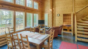 A log cabin interior with a dining area, a television, and a staircase.