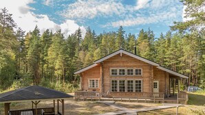 A log cabin with a porch and a covered seating area.