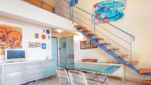 Una cocina moderna con mesa de comedor de vidrio, armarios blancos y una escalera azul.