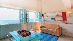 Un espacio habitable compacto con comedor, sofá y vista al mar.