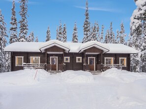 A wooden lodge with two visible entrances, numbered 4A and 4B, surrounded by snow-covered trees.