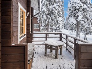 Eine Holzhütte mit einer schneebedeckten Veranda und einer Bank.