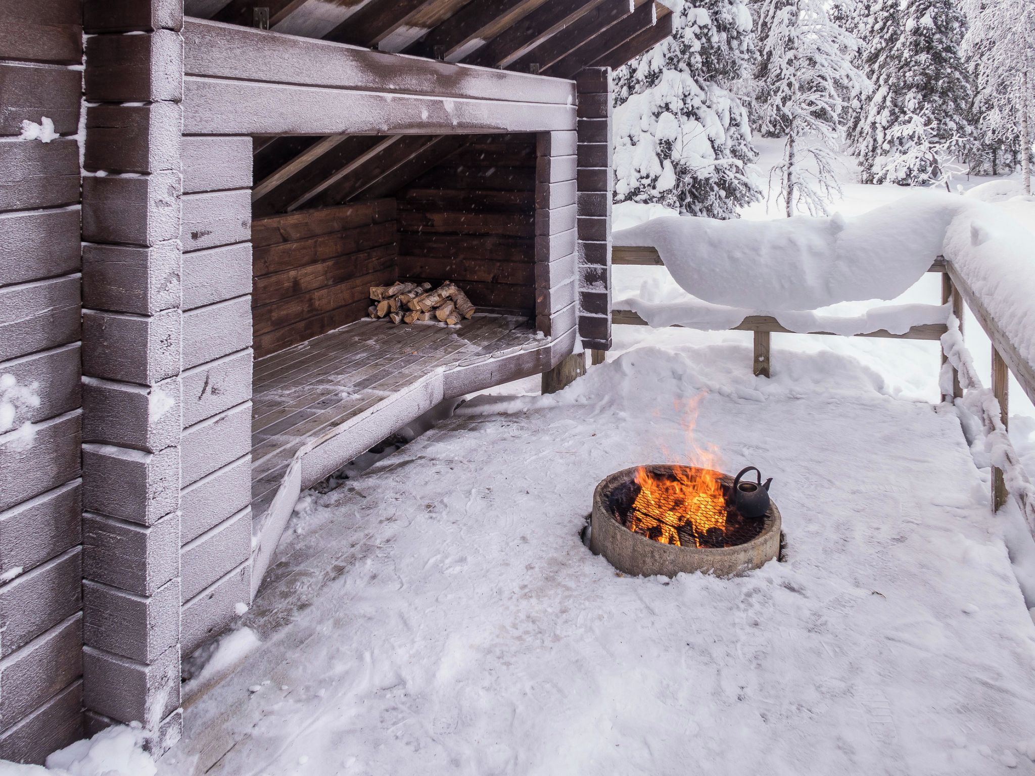 Una baita di legno con camino, paesaggio innevato e una staccionata in legno.