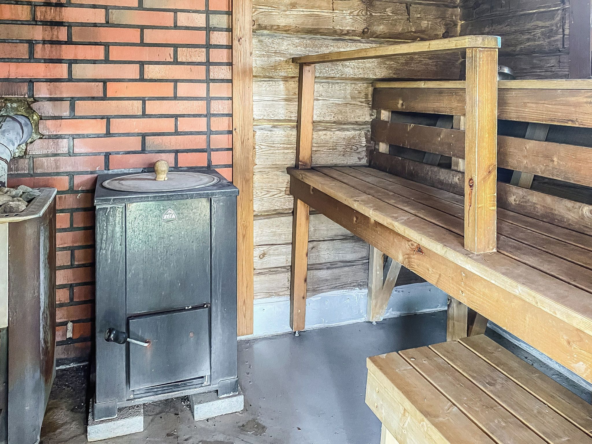 A rustic wooden bench and a metal stove with a lid.