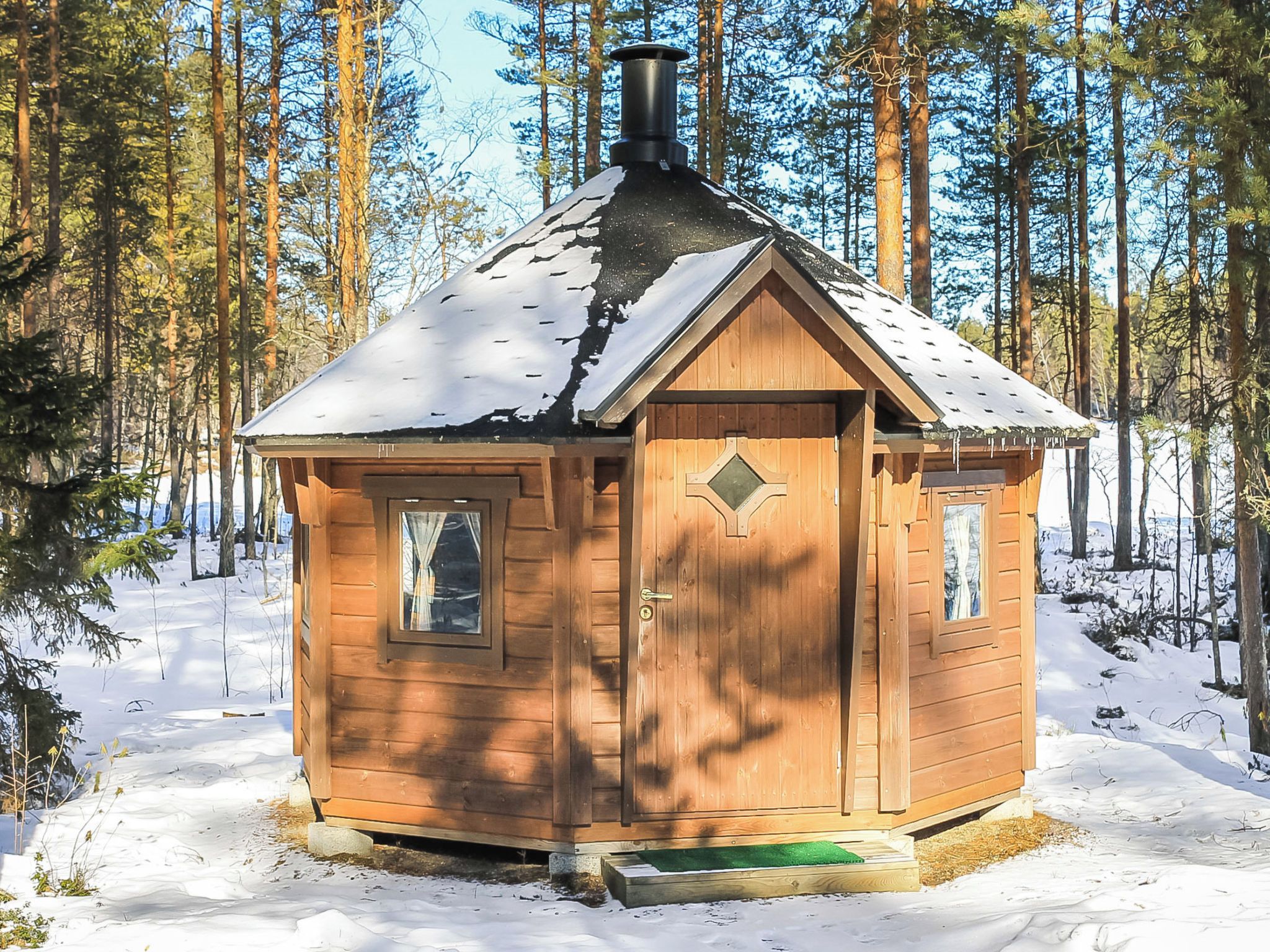 A wooden cabin with a pitched roof, a chimney, and a door with a diamond-shaped window.