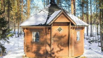 A wooden cabin with a pitched roof, a chimney, and a door with a diamond-shaped window.