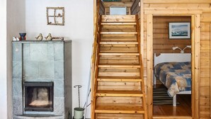 A wooden interior with a fireplace, a staircase, a bed, and a painting on the wall. - Mäntyniemi by Interhome (Konnevesi)