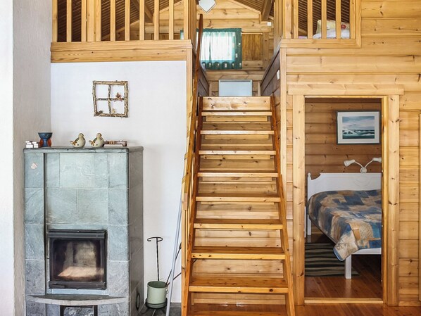 A wooden staircase leading to a loft bedroom with a bed and a view of the sea.