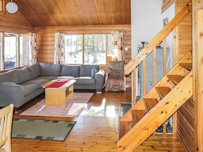Un interior de madera con un sofá, una mesita y una escalera.