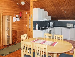 Een houten interieur met een eethoek, keuken en een kast met glaswerk.