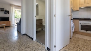 Um apartamento moderno com cozinha, sala de estar com TV e assentos, e varanda com vista.