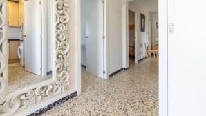 Um corredor com um espelho grande e ricamente decorado, uma área de cozinha e uma sala de jantar.