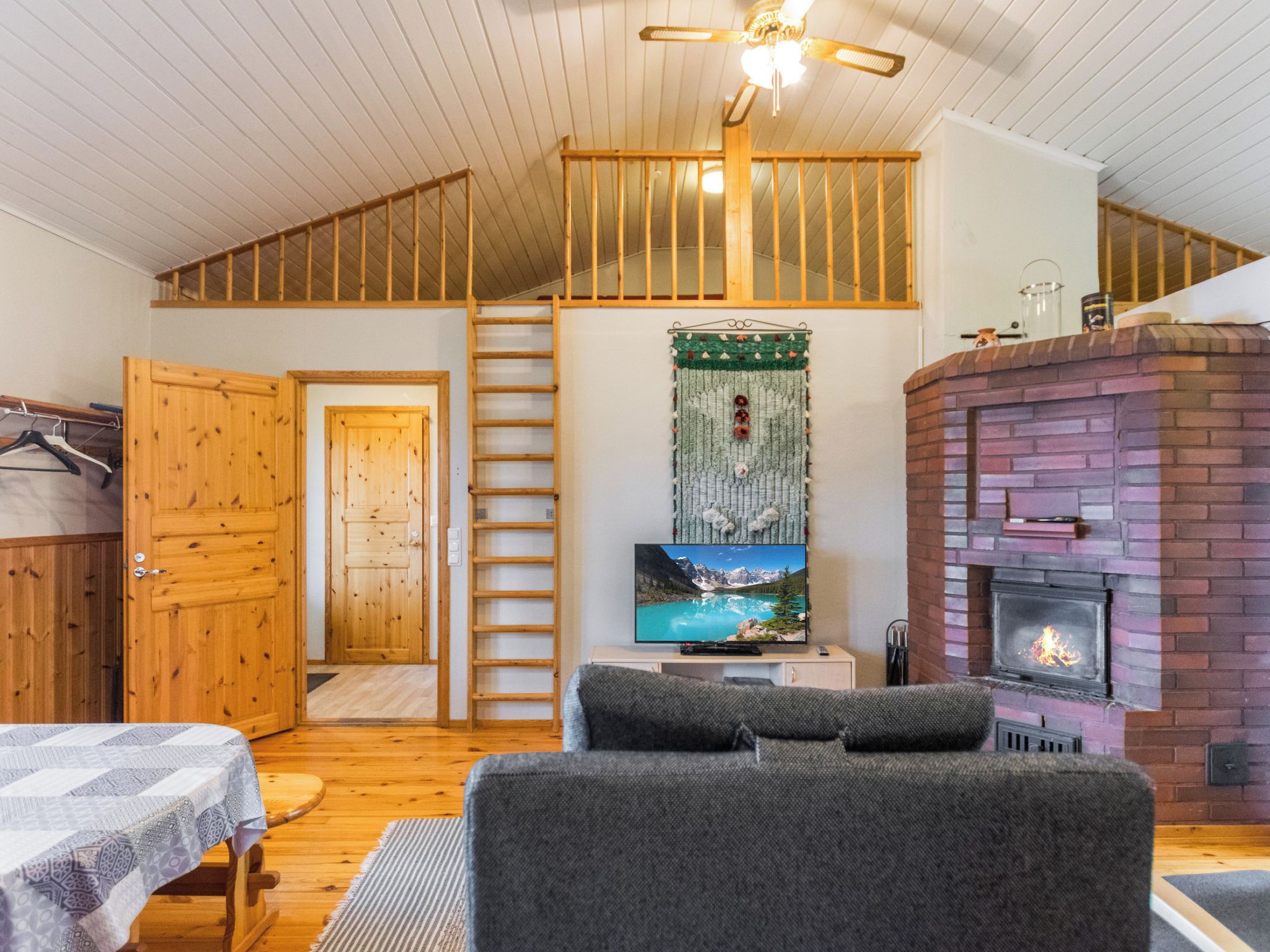 Una habitación acogedora con chimenea, televisión y techo de madera.