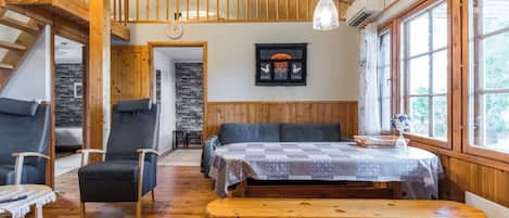 L’intérieur chaleureux d’un chalet avec un banc en bois, deux chaises, une table et un escalier menant à un niveau supérieur.