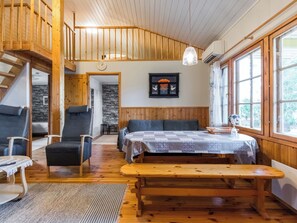 L’intérieur chaleureux d’un chalet avec un banc en bois, deux chaises, une table et un escalier menant à un niveau supérieur.