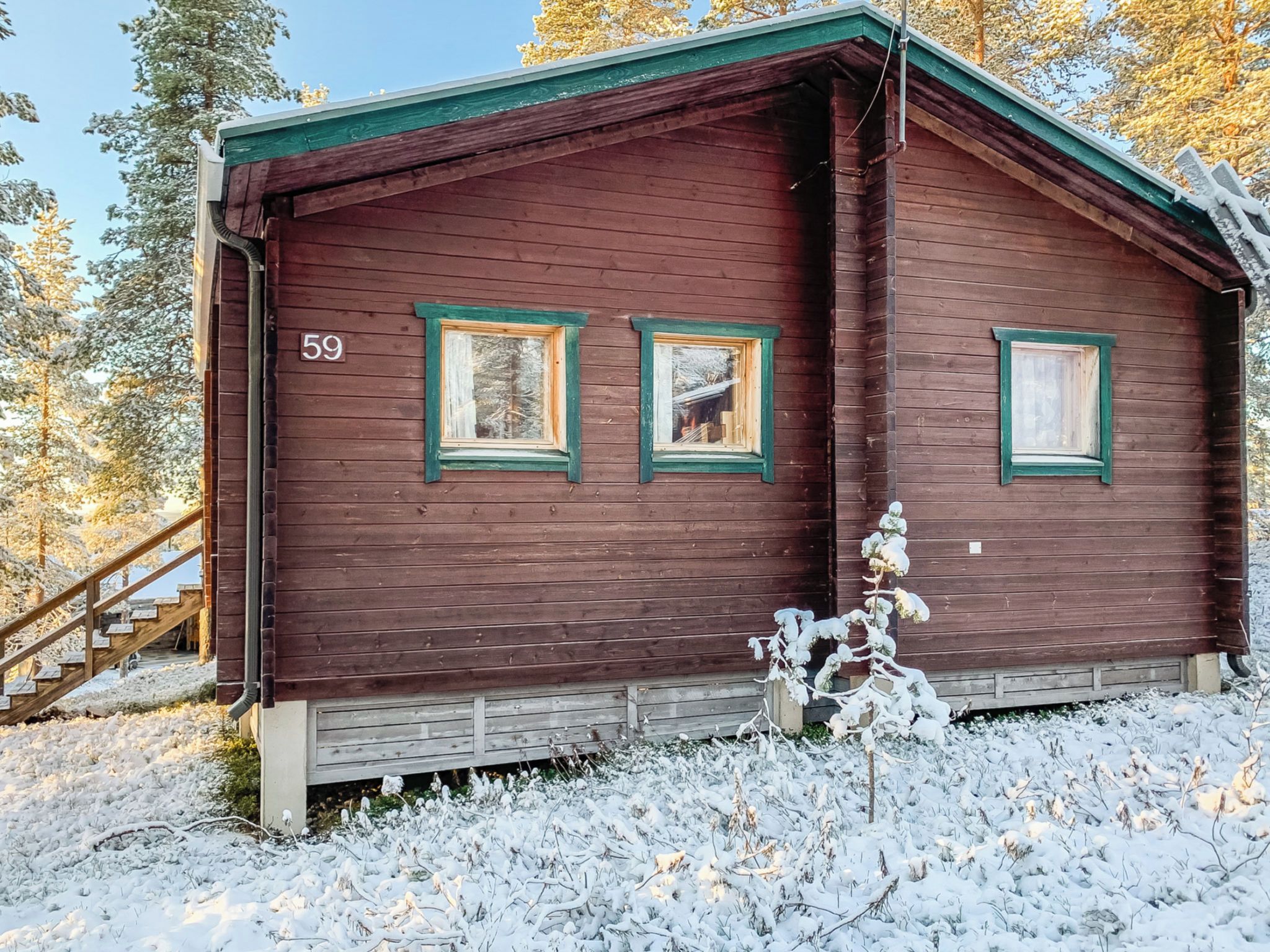 Une cabane en bois avec trois fenêtres, le chiffre « 59 » peint sur le mur et un sol recouvert de neige.