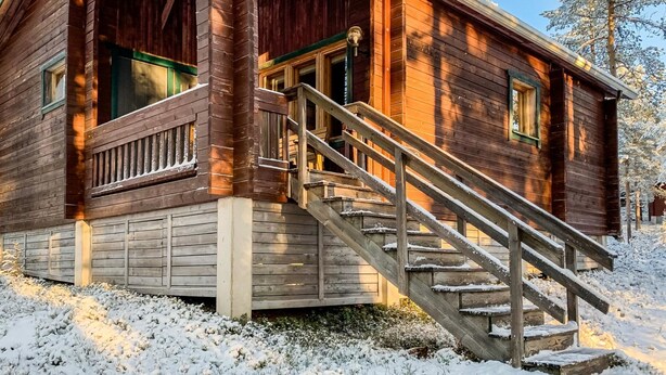 A wooden cabin with a staircase leading to the entrance, surrounded by snow. - Pikku-metso by Interhome (Kuusamo)
