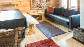 A cozy living room with a sofa, a small table, a rug, and a wall tapestry. - Pikku-metso by Interhome (Kuusamo)