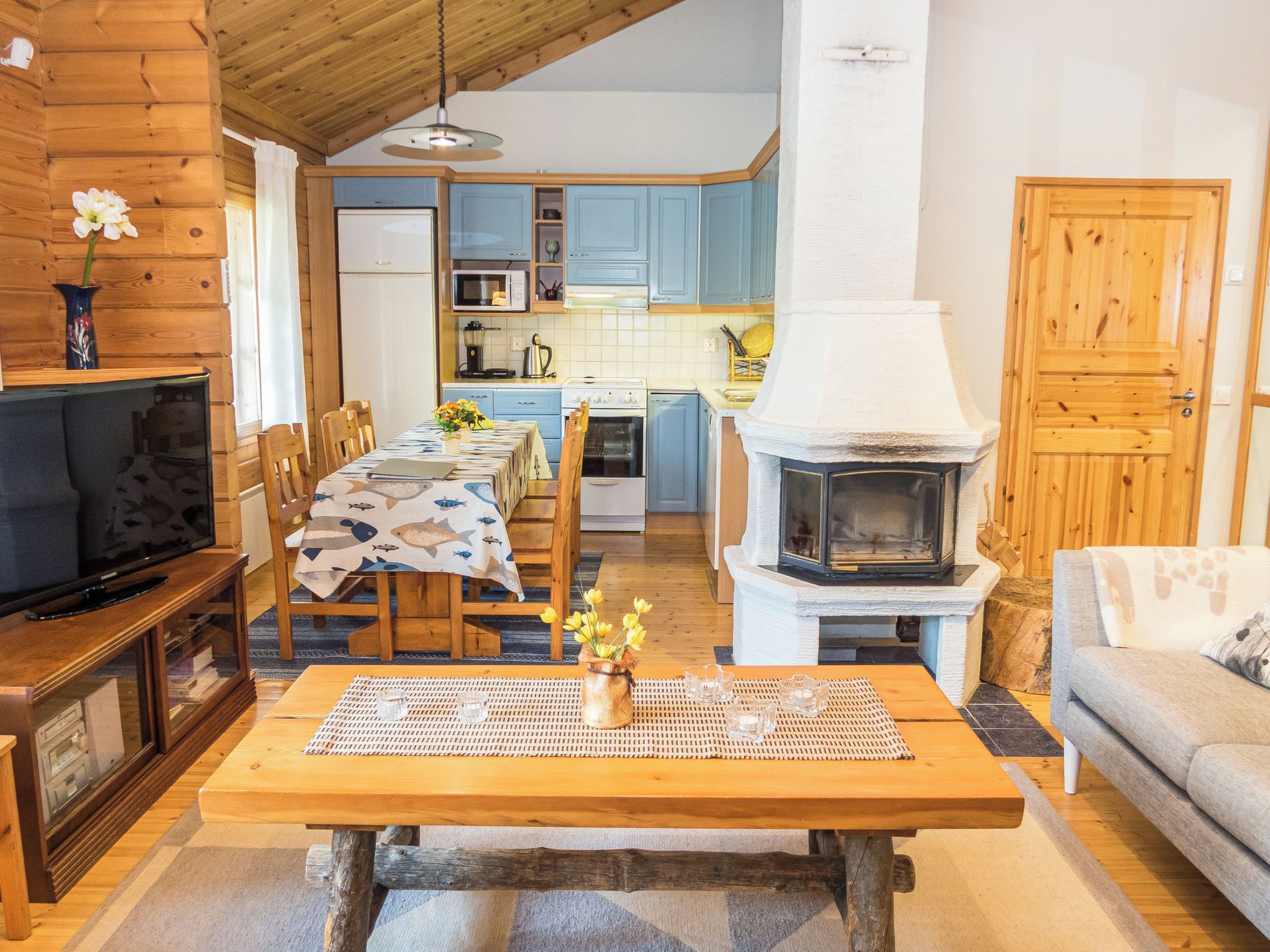 A cozy living room with a wooden table, a television, and a fireplace.