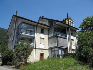 Un immeuble résidentiel à plusieurs étages, doté de grandes fenêtres et de balcons.