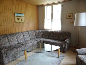 Un salon avec un canapé d’angle, une table basse en verre et une lampe.