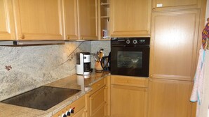 A kitchen with wooden cabinets, a built-in oven, a coffee maker, and a stove.