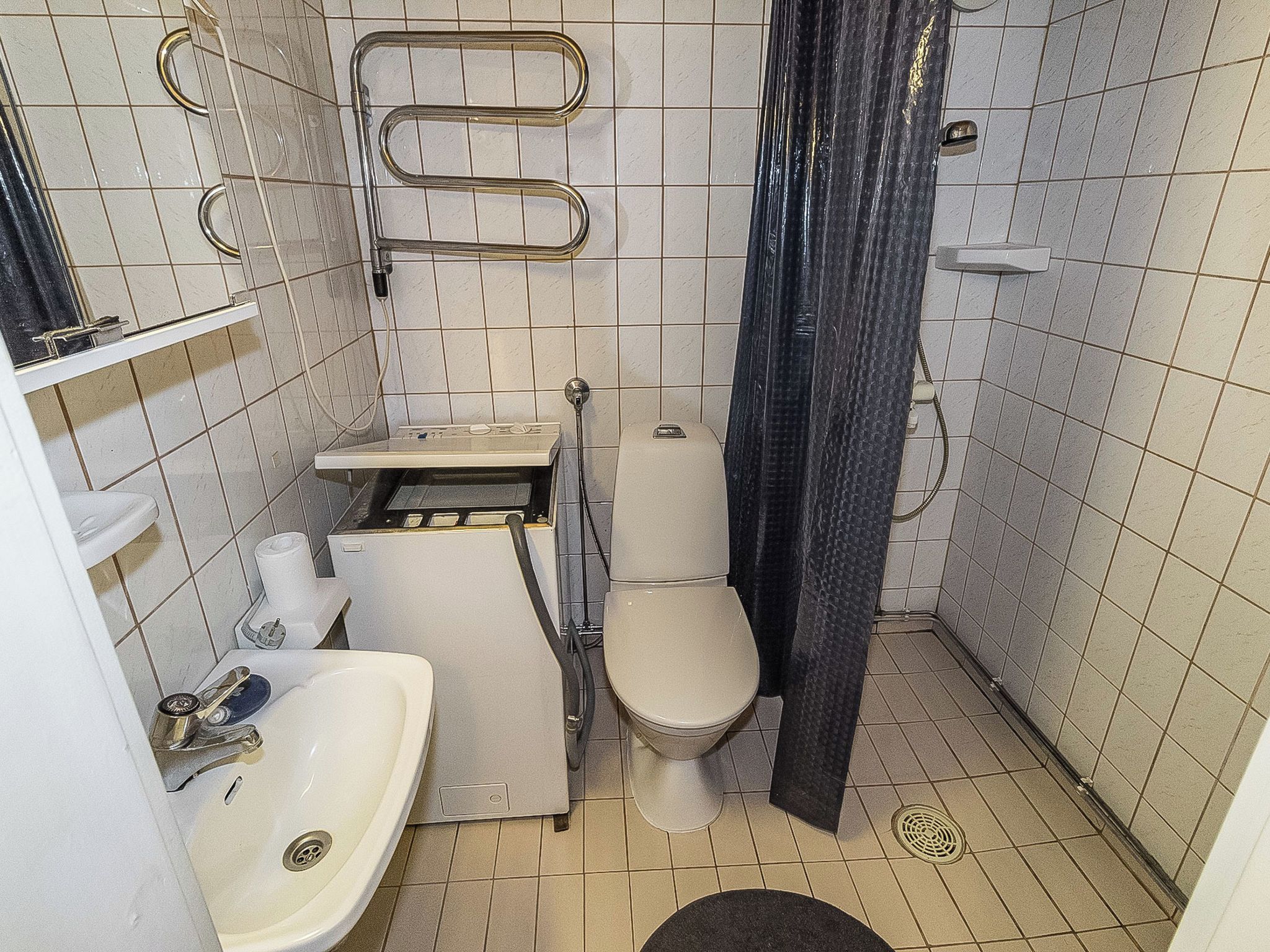 Pieni kylpyhuone, jossa on wc, pesuallas ja suihkutila.
