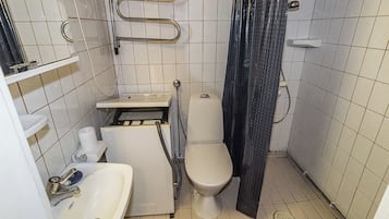 Pieni kylpyhuone, jossa on wc, pesuallas ja suihkutila.