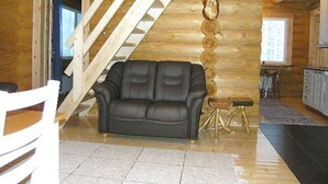 Een blokhut interieur met een bank, een eettafel en een trap.