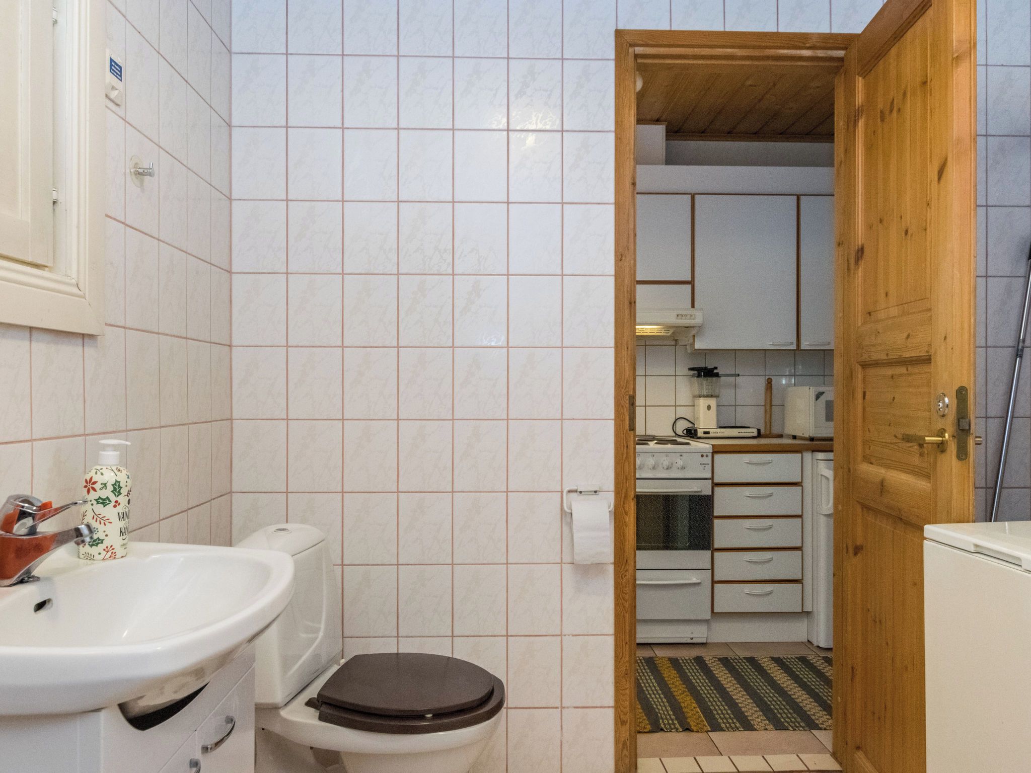 A bathroom with a toilet, sink, and a bottle of soap.