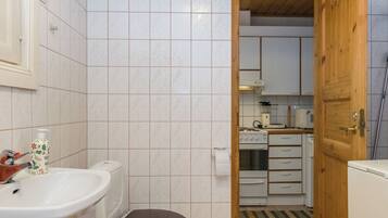 A bathroom with a toilet, sink, and a bottle of soap.
