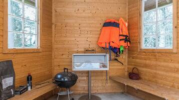 Een houten wand, een grill, een kapstok en een raam in een cabin.
