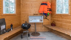 A wooden cabin interior with a grill, a small sink, and a bench. - Mäkimökki by Interhome (Somero)