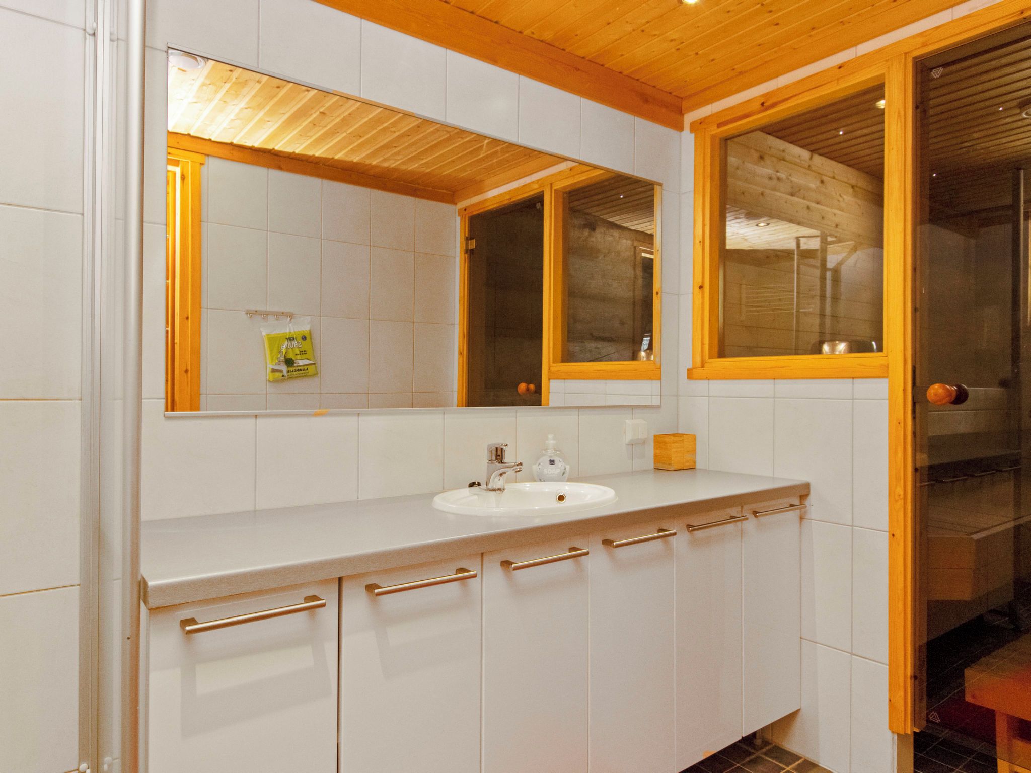 A bathroom with a white sink, a mirror, and wooden cabinets.