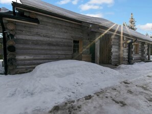 A log cabin with a snow-covered roof and a large pile of snow in front. - Peikkola by Interhome (Kuusamo)