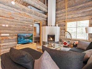 A log cabin interior with a television, sofa, fireplace, and a large window. - Peikkola by Interhome (Kuusamo)