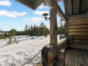 A wooden cabin with a snow-covered deck and a view of a forest. - Peikkola by Interhome (Kuusamo)